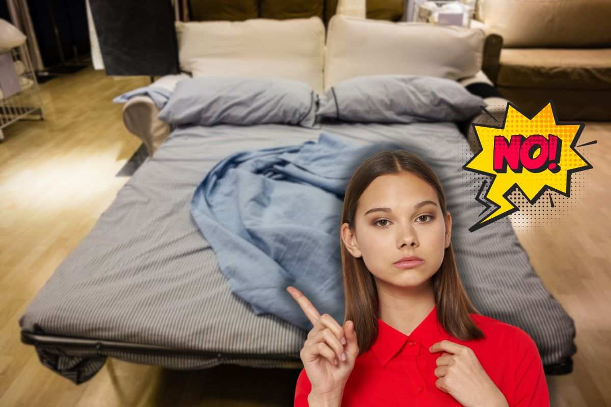 divano letto aperto, scritta no e donna seria che lo indica