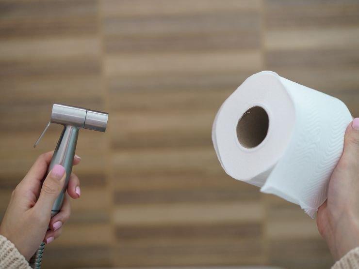 persona che mantiene carta igienica e doccetta