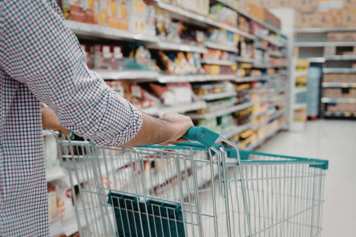 uomo che porta carrello al supermercato